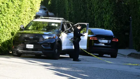 DUTCH/Bauer-Griffin/GCImages A police officer stands by a police car and yellow tape outside of Rihanna's home in Beverly Hills.