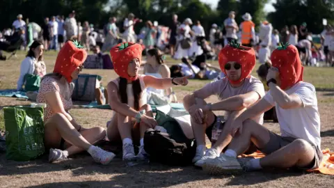 PA Spectators in the queue sporting strawberry hats on day one of the 2025 Wimbledon