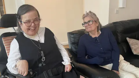 Two women sat side by side in armchairs.