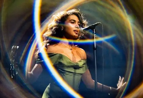 Getty Images Olivia Dean on stage, surrounded by a halo of light