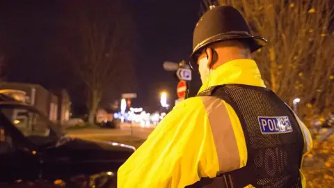 The back of a police officer standing in a street at night