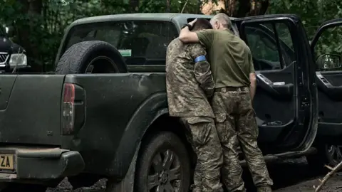 Getty Images Seorang prajurit Ukraina menghibur kawan selama pertempuran di Kursk