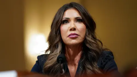 Reuters Kristi Noem attends a House Homeland Security hearing, she stares above the camera in a serious expression.
