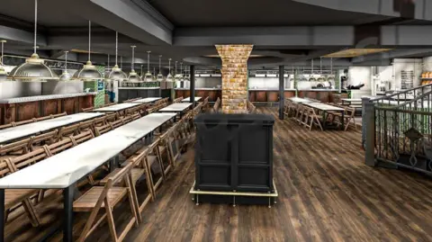 Sandeep Singh Interior of Tower Street Food Hall, Ipswich, showing long trestle tables, with rows of wooden chairs tucked in, on a wooden floor, metal and glass lights above the tables, and kitchen counters on the left and at the back.