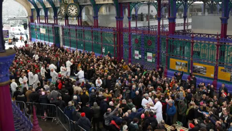 PA Media Hundreds of people in Smithfield Market