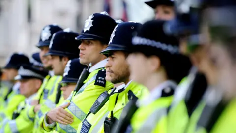 PA Media File image showing a row of Met Police officers in uniform and hi-vis yellow jackets