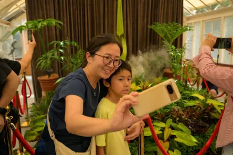 Two visitors pose for a selfie in front of Amorphophallus titanum, famously known as the Corpse Flower seen at the Royal Botanic Garden Sydney