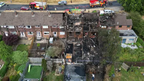 Two burnt out houses and long gardens with fire damage