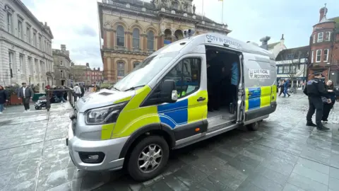 Luke Deal/BBC A police van parked up in the Cornhill area of Ipswich. The van's side door is open and police officers stand nearby. 