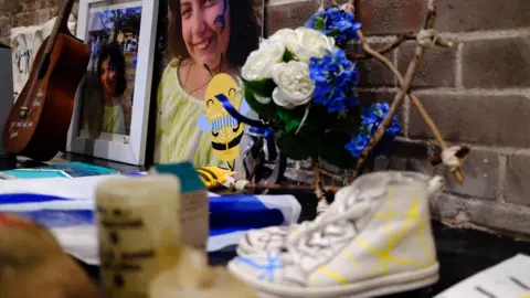 BBC/Katy Watson A pair of white decorated converse sit among other items in front of a picture of Matilda