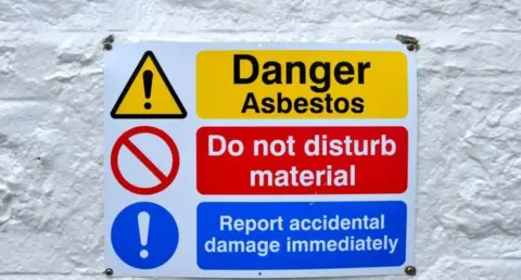 Getty images a sign reading Danger asbestos, do not disturb the material, report immediate contingency damage