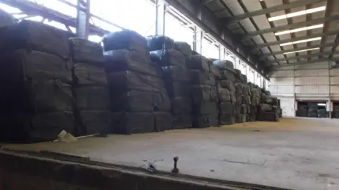 Environment Agency Large stacks of bales of rubbish piled high in a warehouse. 