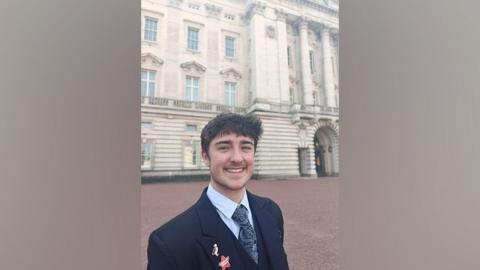 Charlie, 19, pictured smiling outside Buckingham Palace