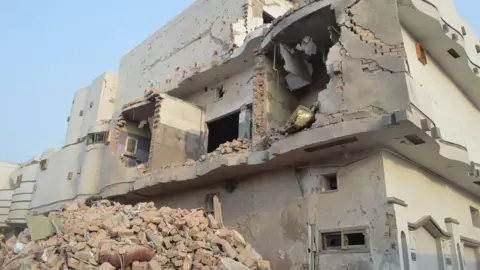 A building is partially demolished, rubble on the ground