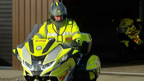 BBC A south west blood bike rider sat on a motorbike in front of the charity's Devon headquarters in Plymouth