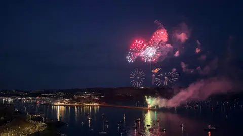 Fireworks exploding in the night sky over the waterfront.