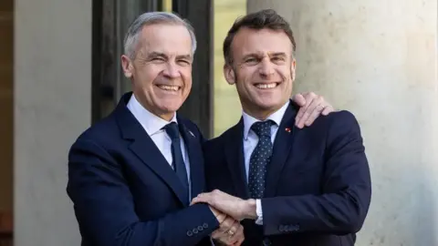 French President Emmanuel Macron (R) shakes hand with Canadian Prime Minister Mark Carney (L) at the Elysee Palace in Paris