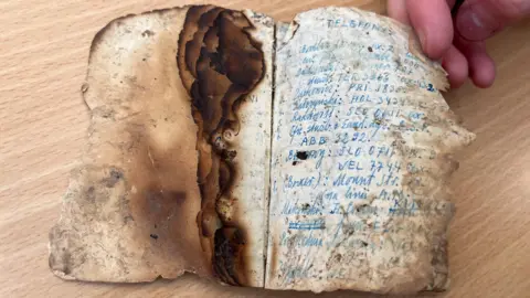 a severely charred small log book, handwritten notes are believed to be missions flown by the airman during and after the war 