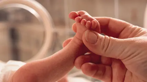 baby in premature baby unit - hand holding tiny foot