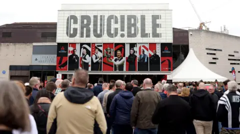 Getty Images A crowd of people queue to enter the Crucible Theatre in Sheffield. Many are wearing coats.