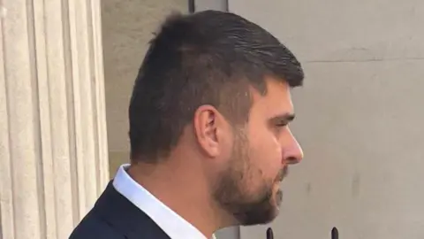 Joseph Gibson wearing a dark suit and white shirt leaves court