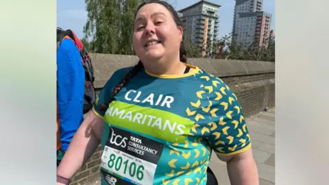 handout Clair has brown hair in a plait, she is wearing a green Samaritans training top
