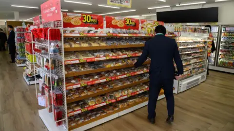 Getty Images Back view of a man reaching for a bread on the shelf of a convenience store