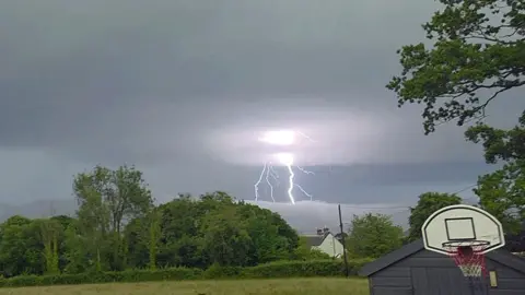 Ian Price | BBC Weather Watchers Lightning over trees and roofs at Caernarfon, Gwynedd