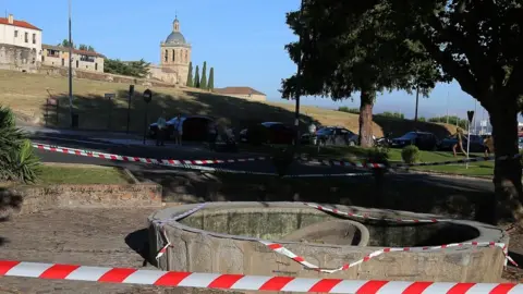 A cordon surrounds the broken fountain, which sees the top of the fountain collapsed into its base,  with a backdrop of Ciudad Rodrigo