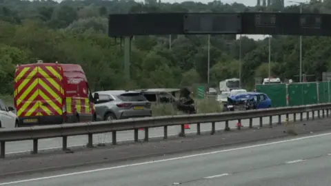 Cars by the roadside, with one burnt out