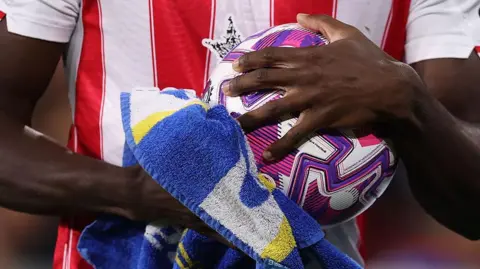 A close-up of Brentford's Michael Kayode drying the ball with a towel