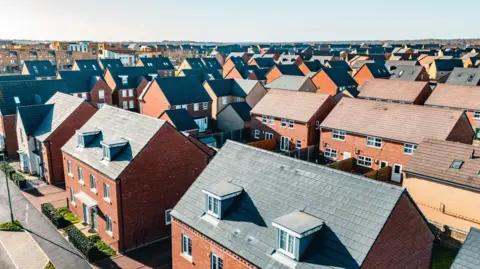 Getty Images An aerial view of a group of red brick houses. The sky is blue.