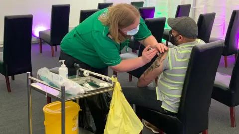 A paramedic administering a Covid-19 vaccination into a man's arm