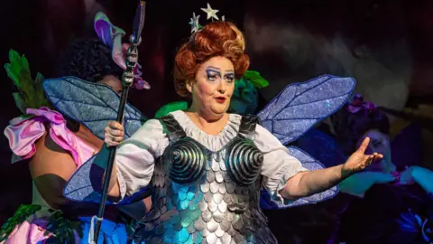Catherine Wyn-Rogers as Queen of the Fairies performs on stage during a dress rehearsal of Iolanthe by Gilbert and and Sullivan. She is wearing an armour-style dress and a white blouse.