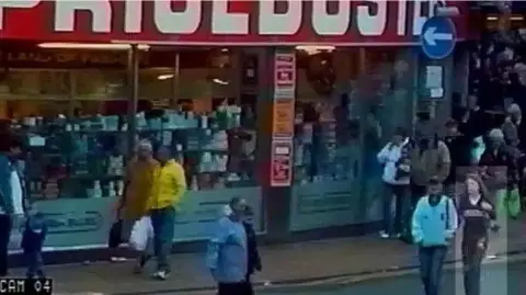 Lancashire Police A CCTV image of Charlene walking with her sister outside a shop in Blackpool. The pair are crossing the road. They are surrounded by other shoppers and the image is grainy.