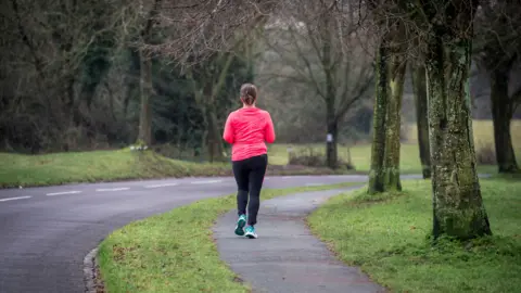 PA A woman running along a path through The Downs