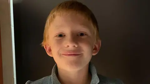 Zac with blonde hair smiling at the camera