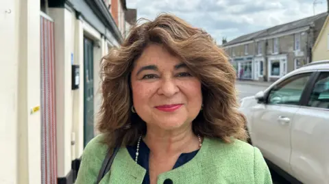 Ben Parker/BBC A woman wearing a green jacket over a blue top. 
