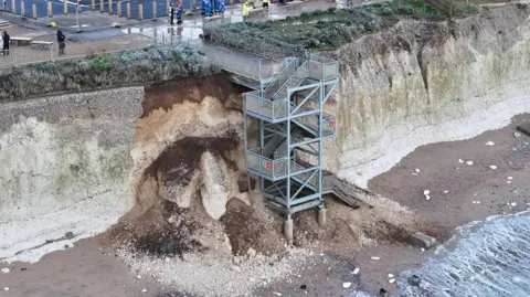 Eddie Mitchell Aerial image of white cliffs. Part of cliffs around a staircase leading from the top to the beach have collapsed onto the beach below.