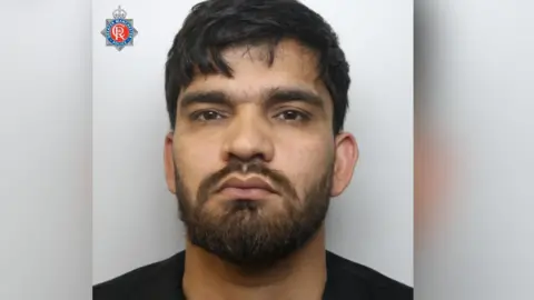 GMP Man with short hair and black beard in police mugshot.