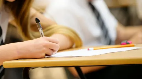 Getty Images/JohnnyGreig Secondary school child sitting at desk during exam