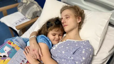 Family picture Poppy in her princess dress cuddling her mother in hospital