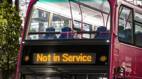 PA Media A pink Translink metro bus, on the front of it are the words not in service in yellow.
