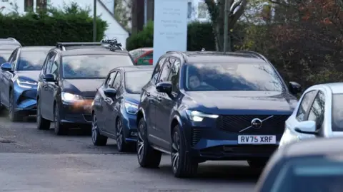 PA Media A row of cars in a queue. The driver of one car can be seen in one window.