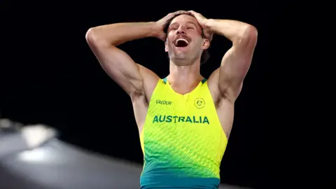 Getty Images Kurtis Marschall of Team Australia in yellow Australian kit, is smiling broadly, his hands on his head. He looks very happy and has a nice moustache.