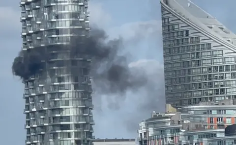 Thick black smoke billows out the side of a 45-storey tower block in east London