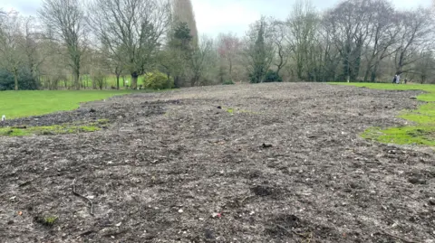 ldrs Large pile of dirt and waste material on what was once a green field.