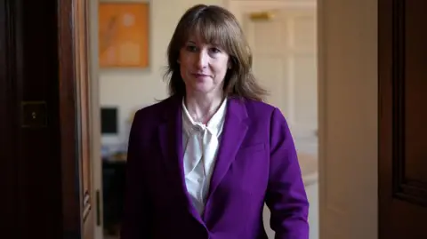 PA Media A woman with brown hair. She is wearing a purople jacket over a white shirt