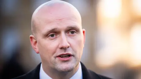 PA Media Close up of a bald man with his mouth opened in conversation.