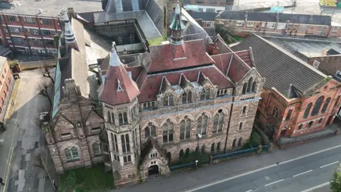 Andy Savage A Victorian building which is red brick with church-style windows and a spire.It is a former art school building in Derby.
